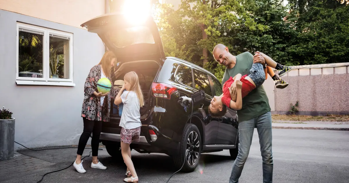 Eine Familie packt gemeinsam ihr E-Auto für den Urlaub.